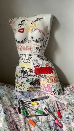 a white mannequin sitting on top of a bed covered in lots of writing