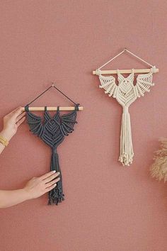 a woman is holding a small piece of yarn next to a wall hanging with a tassel