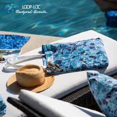 a hat and sunglasses sitting on top of a chair next to a pool with blue water