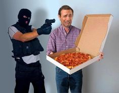 a man holding a box with a pizza in it and another person wearing a mask behind him