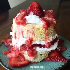 a cake with strawberries and whipped cream on top is sitting on a blue plate