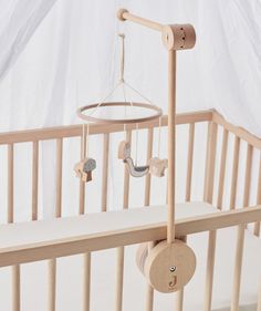 a baby crib with a mobile hanging from it's side, in front of a white background