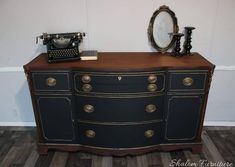 a black and gold painted dresser with an antique typewriter on top