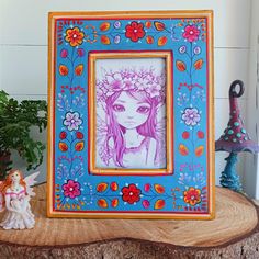 a colorful picture frame sitting on top of a wooden table next to a potted plant