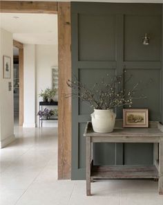 a vase with flowers sitting on top of a wooden table in front of a doorway