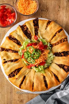 a large pizza pie on a white plate with toppings around the edges and in bowls