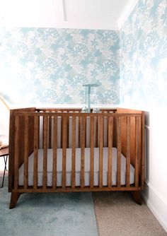 a baby crib in the corner of a room with blue and white wallpaper