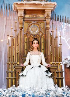 a woman in a white dress sitting on a throne