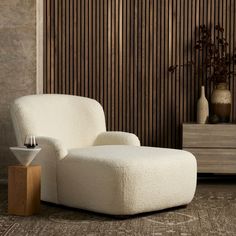 a white chair sitting on top of a wooden floor next to a vase filled with flowers