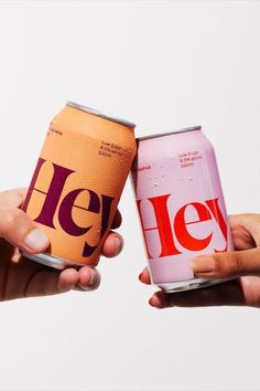 two people holding up cans of heine and pink sodas with the word heine on them