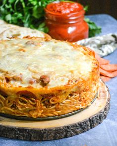 a pizza covered in cheese and sauce on top of a wooden platter next to vegetables