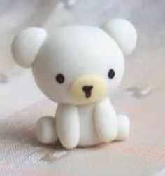 a small white teddy bear sitting on top of a bed