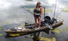 a woman standing on top of a kayak holding a fishing pole and two rods