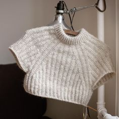 a white sweater hanging from a hook on a wall