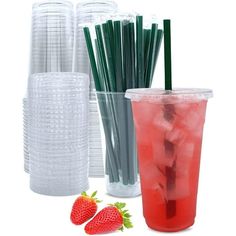 there are many plastic cups and straws next to each other with strawberries on the side