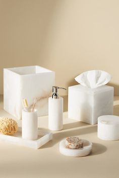 bathroom accessories including soap dispenser, toothbrush holder and tissue box on beige background