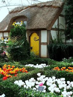 a house with a yellow door surrounded by flowers