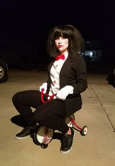 a woman dressed in black and white sitting on top of a wheel chair with a red handlebar