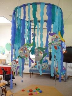 a room filled with lots of blue and green decorations hanging from the ceiling next to a table