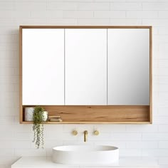 a white sink sitting under a bathroom mirror next to a wall mounted faucet