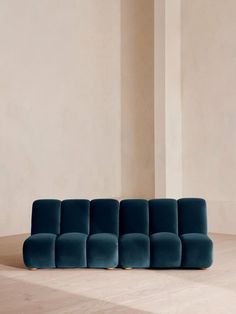 a blue couch sitting on top of a hard wood floor next to a white wall