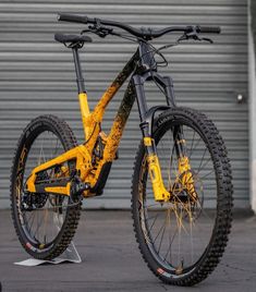 a yellow mountain bike parked in front of a garage door with no wheels on it