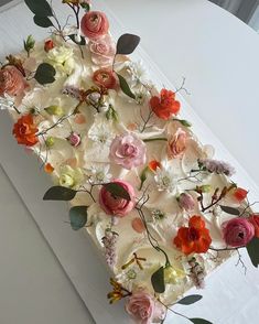 a piece of cake decorated with flowers and greenery on top of a white table