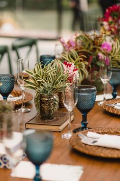 a wooden table topped with plates and glasses filled with flowers on top of each other