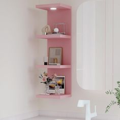 a pink shelf with pictures and flowers on it next to a white sink in a bathroom