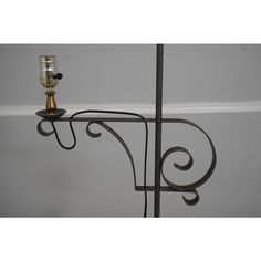 an iron candle holder with two candles on it's sides and a metal rod