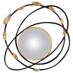 a round mirror sitting on top of a black leather cord with leaves hanging from it