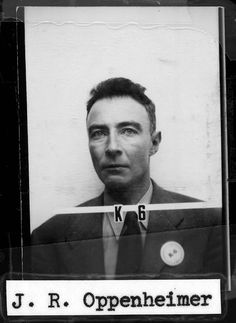 an old black and white photo of a man in a suit holding a license plate