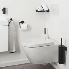 a white toilet sitting in a bathroom next to a black and white towel dispenser