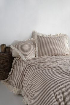 a bed with two pillows on top of it next to a night stand and lamp