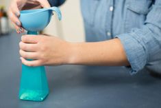 a person is pouring something into a blue vase