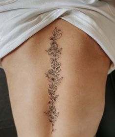 a woman's lower back tattoo with flowers on her left side ribcage