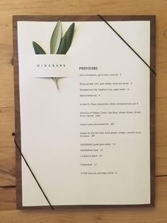 the menu is laid out on top of a piece of paper with a green plant sticking out of it