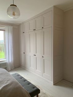 an empty bedroom with white walls and cabinets in the corner, along with a bench