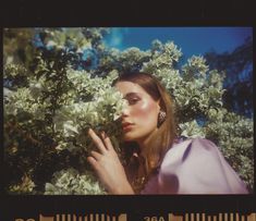 a woman standing in front of some bushes