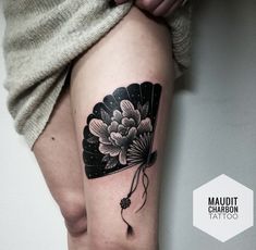 a woman's leg with a fan tattoo on her left thigh and flowers in the middle