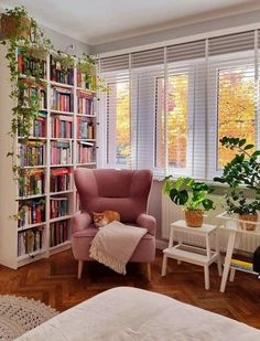 a living room filled with lots of furniture and bookshelves next to a window