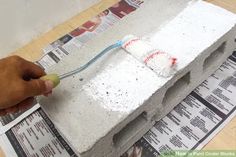 a person using a toothbrush to brush the cement on top of a newspaper page