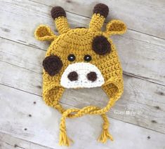 a crocheted giraffe hat is shown on a wooden surface