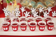 mickey mouse cupcakes are on a tray with red cups and white polka dots