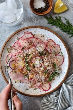 a person is holding a spoon over a plate of food with radishes and herbs