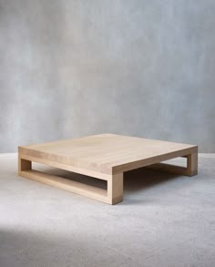 a wooden coffee table sitting on top of a white carpeted floor next to a gray wall