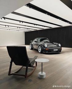 two cars parked in an empty room with wooden flooring and white walls, next to a black rocking chair