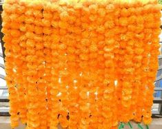 an arrangement of orange flowers hanging from the side of a building