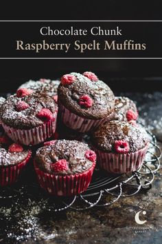 chocolate chunk raspberry spelt muffins on a wire rack with powdered sugar