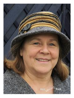 a woman wearing a hat with buttons on the brim and smiling at the camera